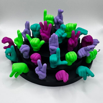 Set of lime green, magnet, purple, teal hand gesture figures on a black base