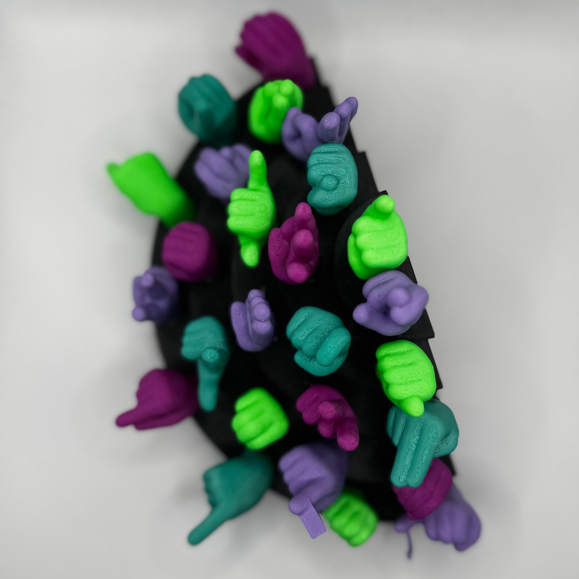 Set of lime green, magnet, purple, teal hand gesture figures on a black base