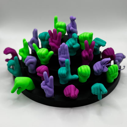 Set of lime green, magnet, purple, teal hand gesture figures on a black base