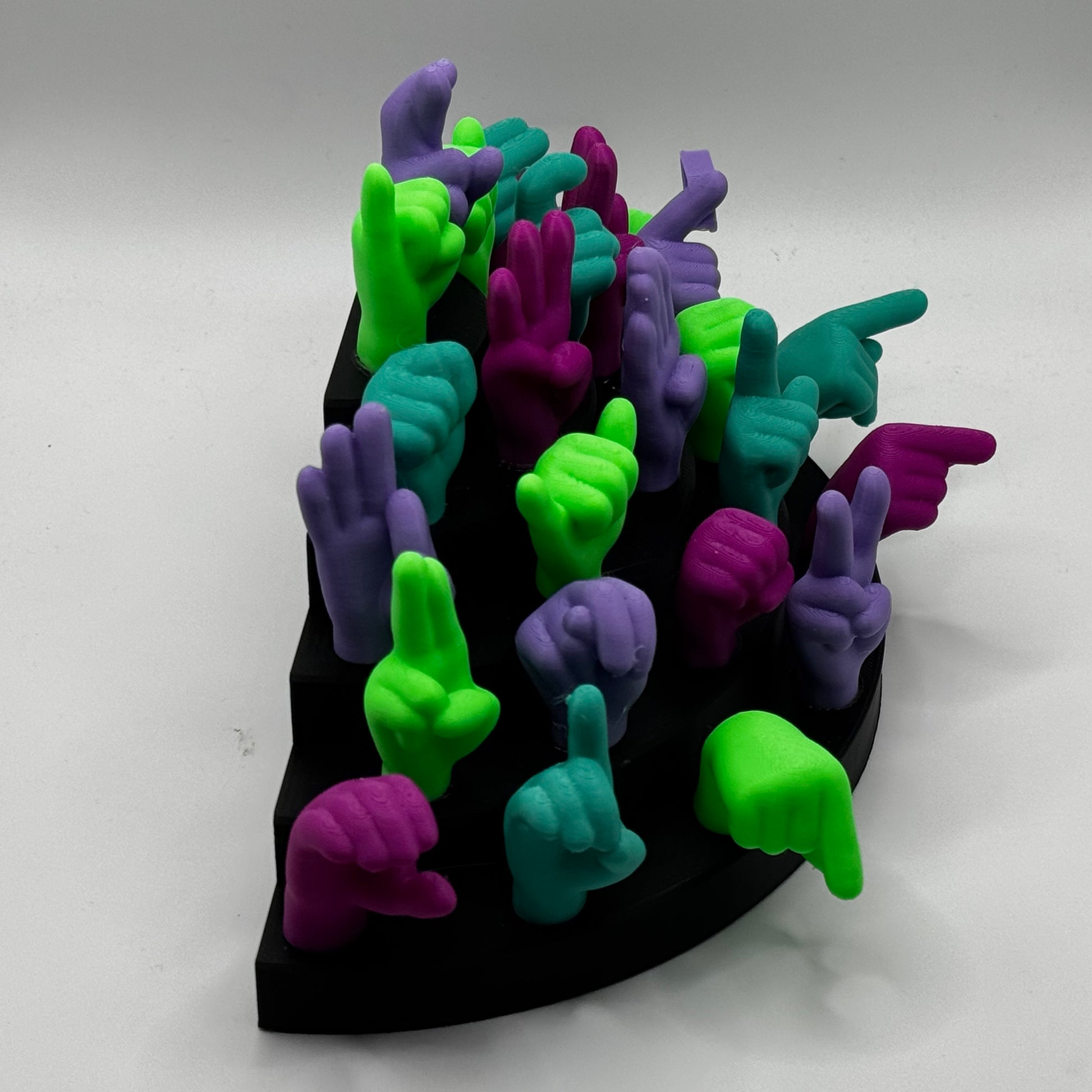 Set of lime green, magnet, purple, teal hand gesture figures on a black base