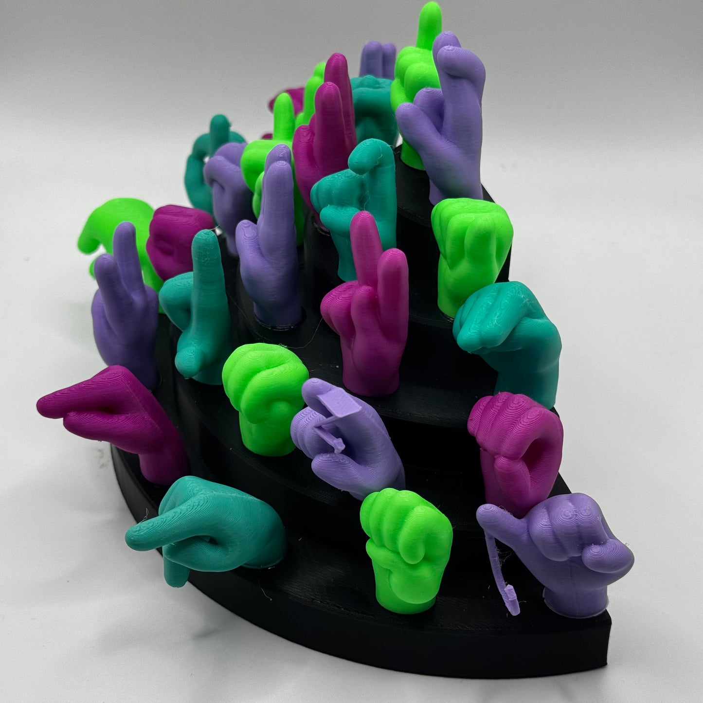 Set of lime green, magnet, purple, teal hand gesture figures on a black base