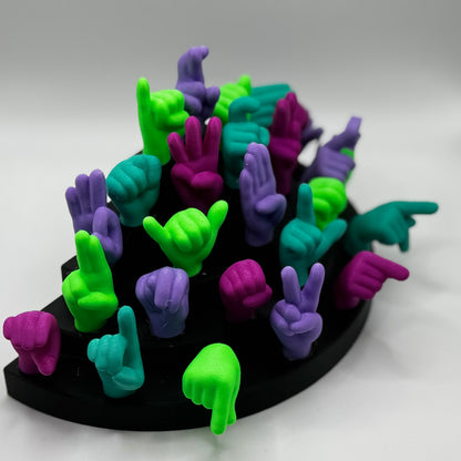 Set of lime green, magnet, purple, teal hand gesture figures on a black base
