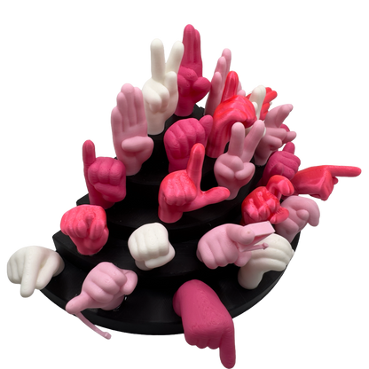 Set of pink, magnet and white hand gesture figures on a black base